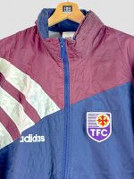 Gros plan sur un kway rétro TFC 1995 original – détail du logo du club violet