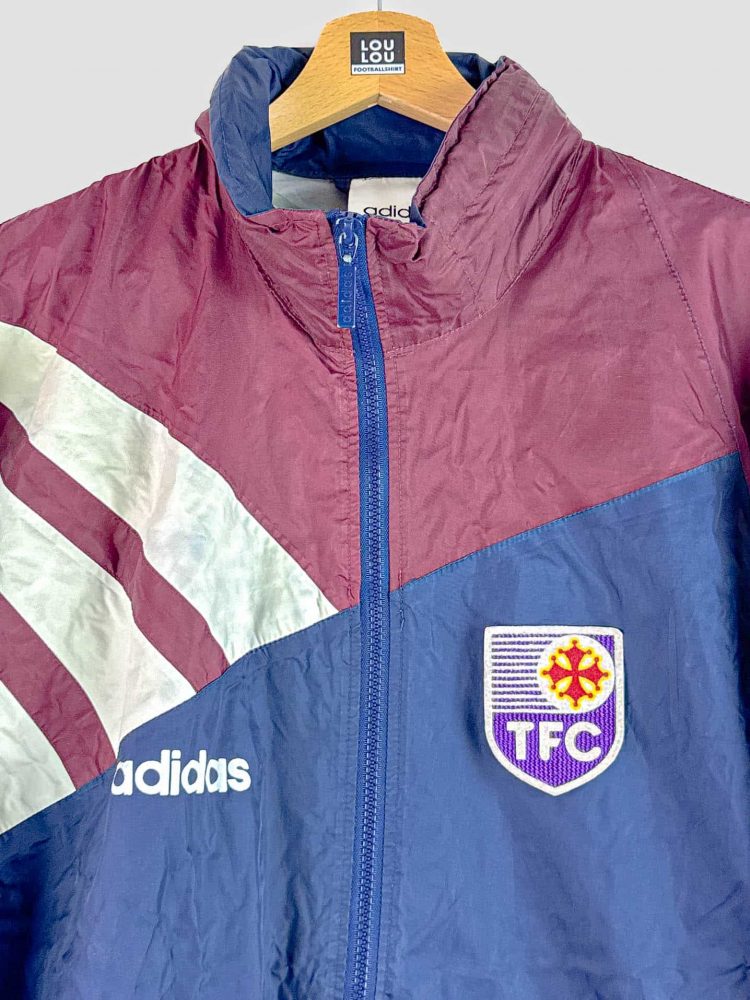 Gros plan sur un kway rétro TFC 1995 original – détail du logo du club violet