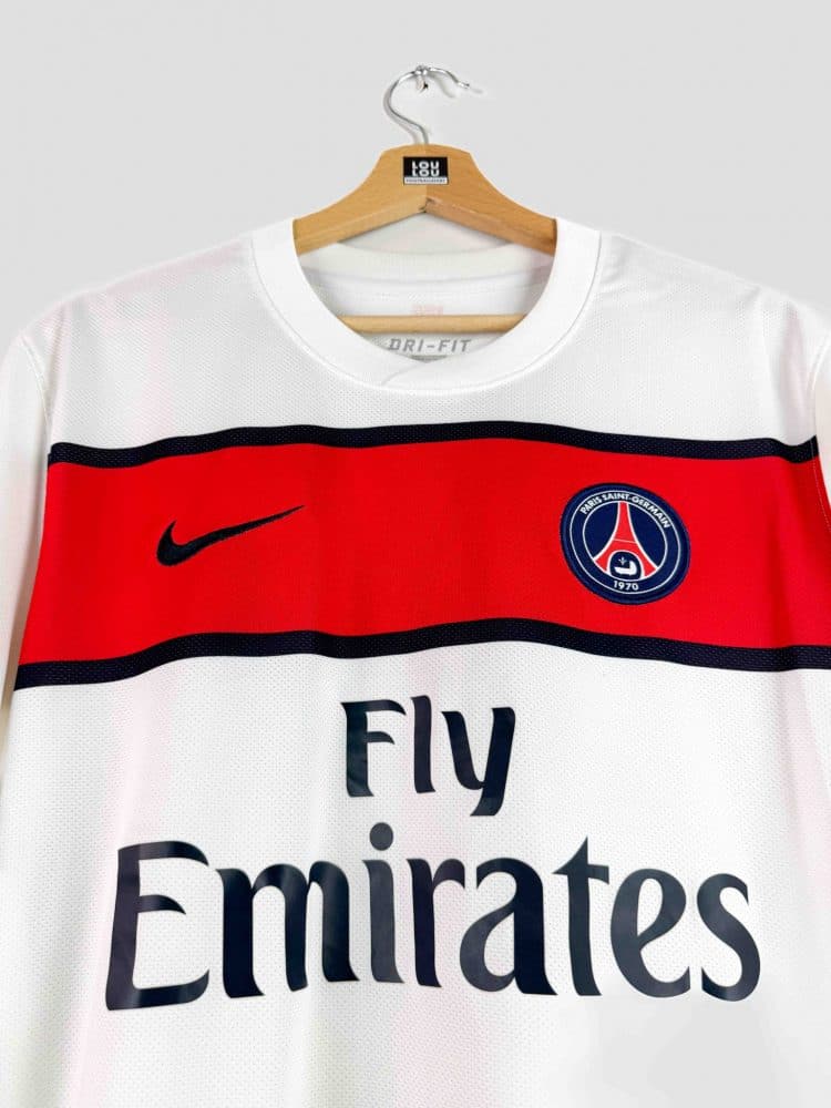 Gros plan sur l’inscription du sponsor Fly Emirates en lettres noires sous la bande rouge du maillot PSG 2011-2012.