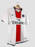 Détail de la bande rouge verticale du maillot PSG 2007-2008 vintage, bordée de liserés bleu marine, illustrant le design Hechter inversé de cette saison.